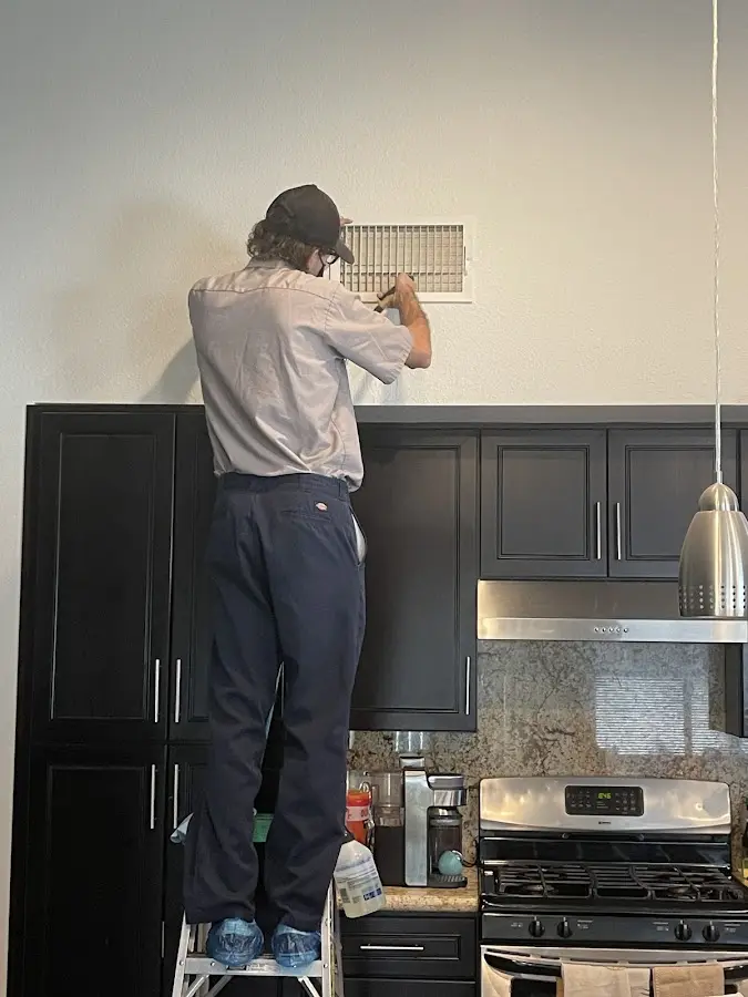 Technician inspecting an air vent during HVAC service in Topsfield